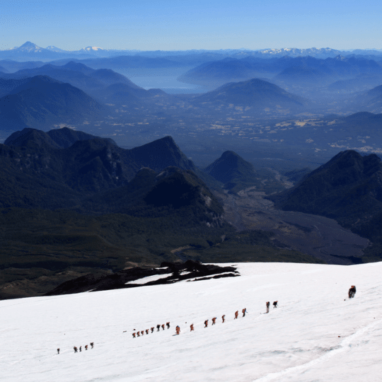 Grupo ascendiendo montaña nevada en Pucón, aventura al aire libre.